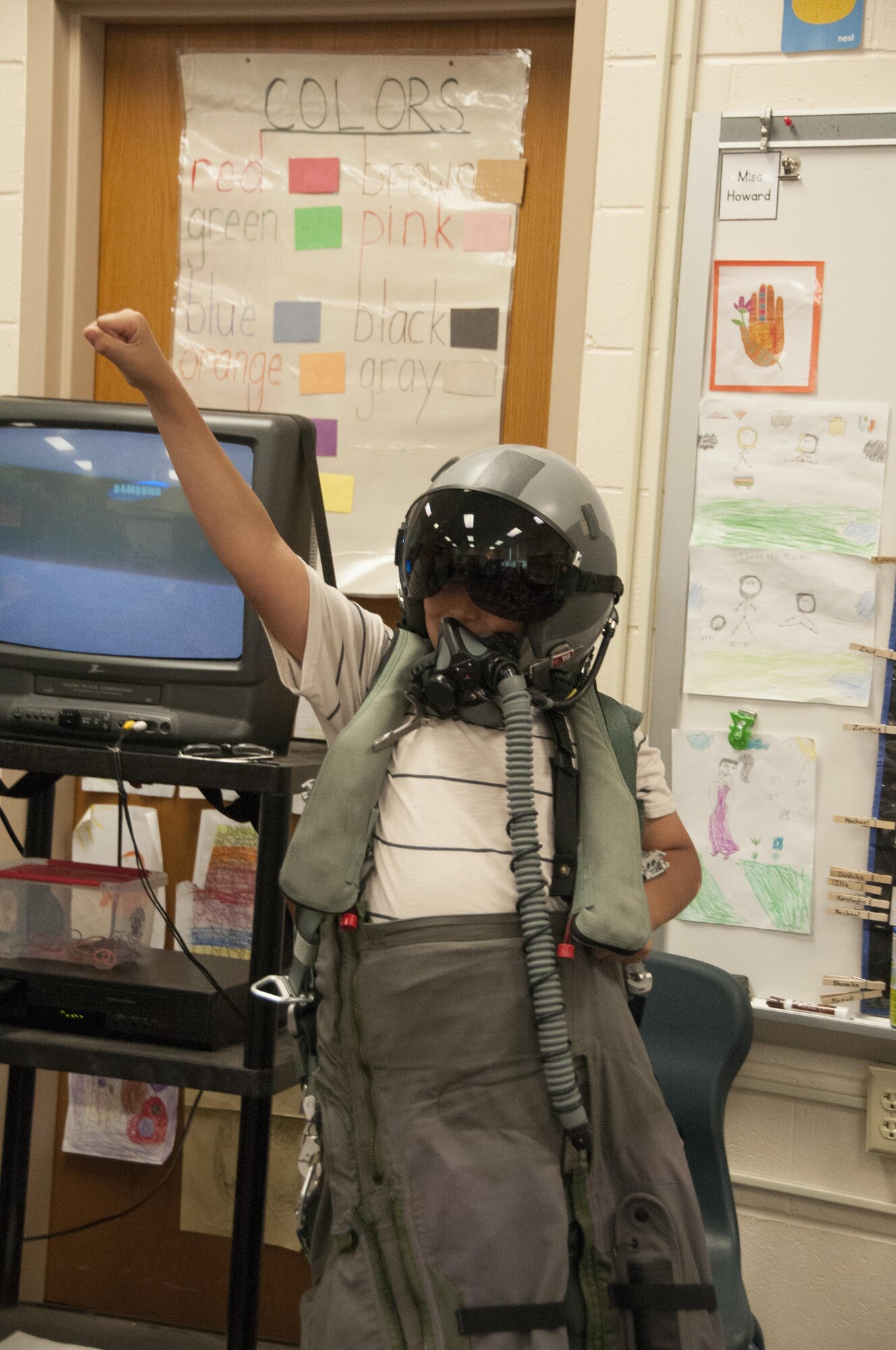 A 10-year-old Hadi Al Nassar, cheers as he wears a 104th Fighter Wing flight suit and aviator helmet as the honoree pilot of the day, June 26, 2017. Tom Bladen, 104th Fighter Wing operations group commander, visits refugee students at Highland Elementary School in Westfield, Massachusetts. The visit served as a means to help the children understand why they hear the loud screeching F15 jets flying overhead when playing outside and to help them understand the 104th Fighter Wing flies to protect. (U.S. Air National Guard photo by Senior Master Sgt. Julie Avey)