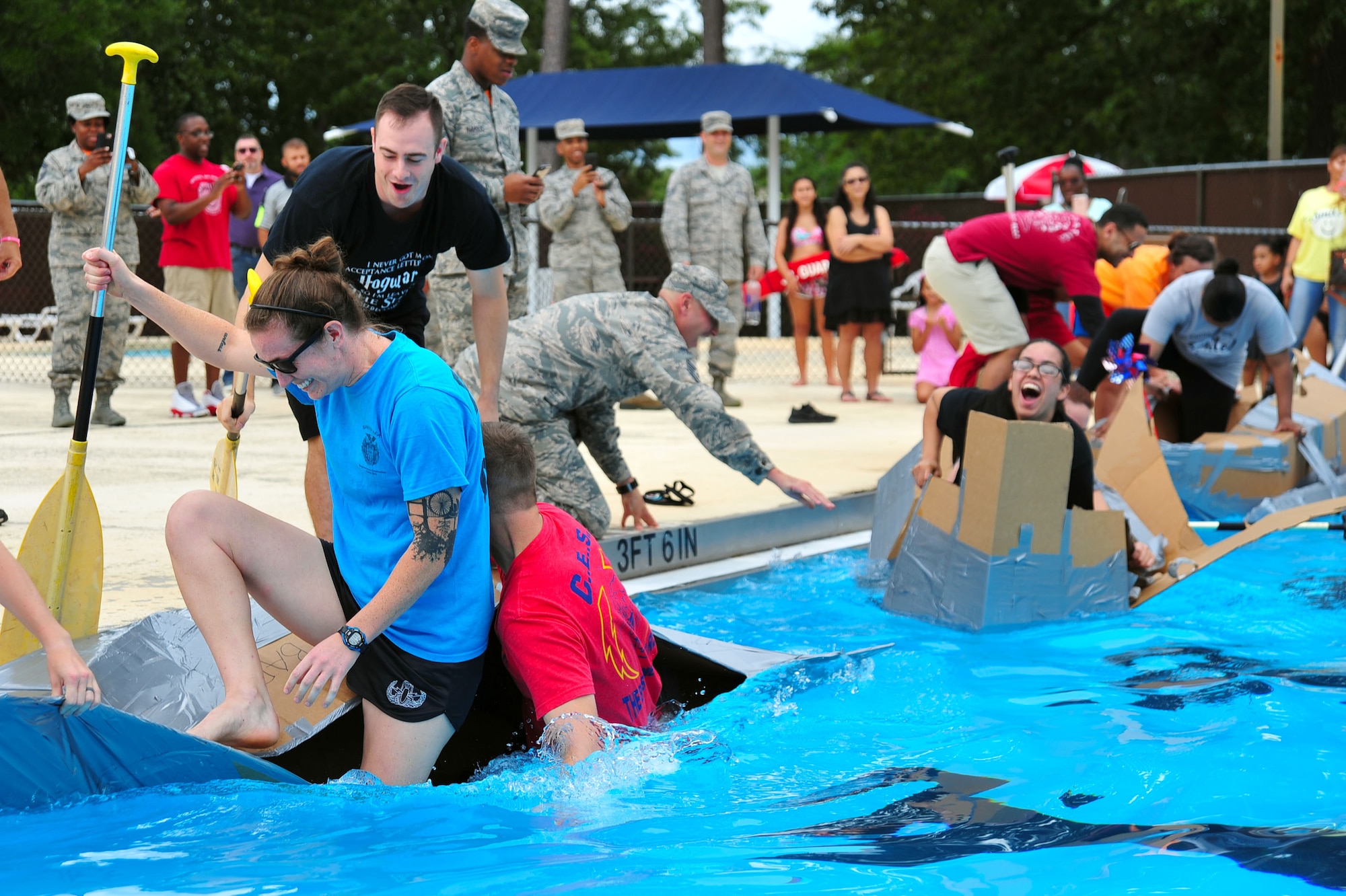 Team Shaw Airmen climb into cardboard boats during the Cardboard Regatta at the Freedom Bash at Shaw Air Force Base, S.C., June 30, 2017. Each four-person team competed in the relay race to win a paddle-shaped trophy and cash prizes. (U.S. Air Force photo by Airman 1st Class Kathryn R.C. Reaves)