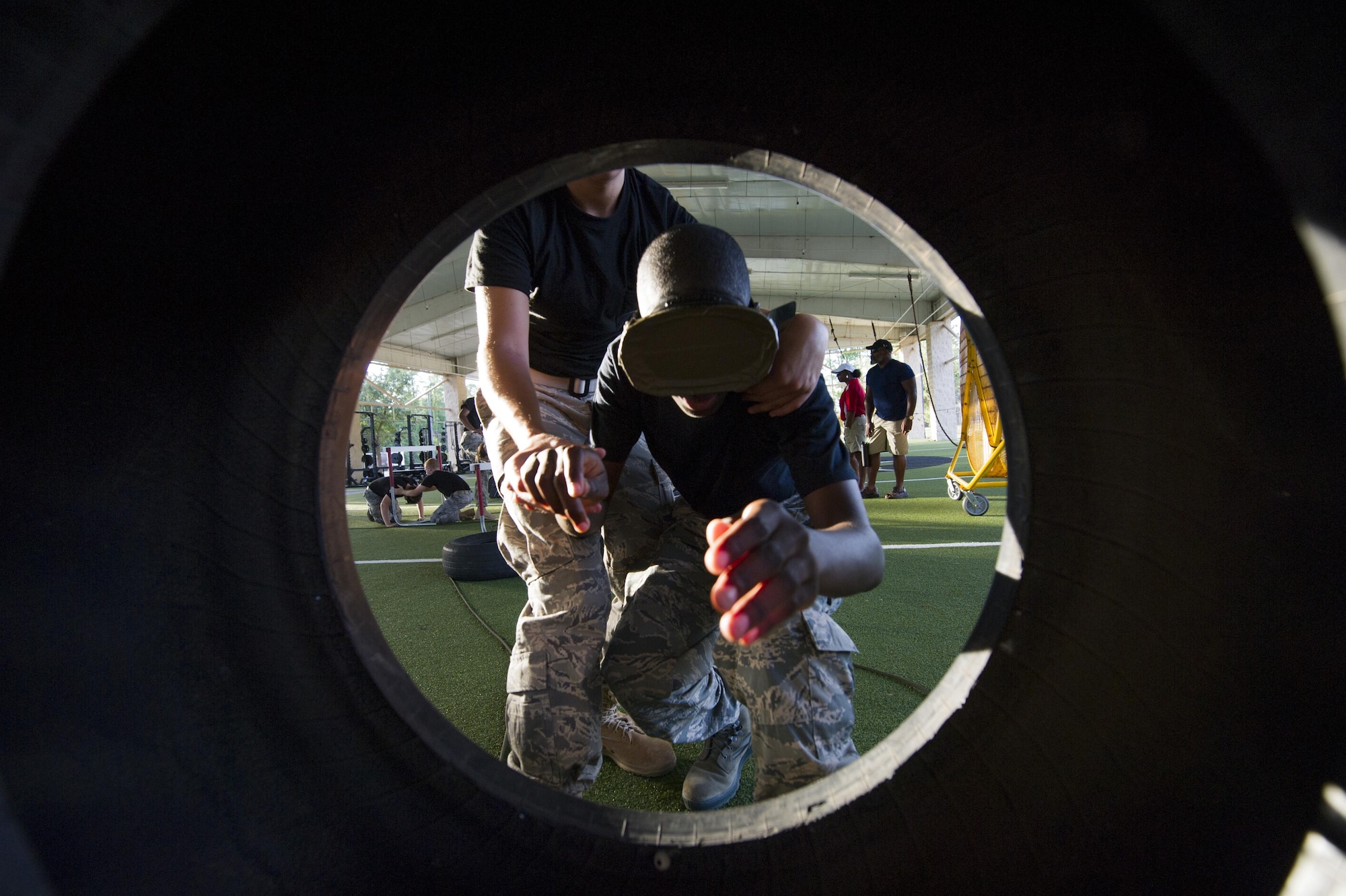 A blindfolded Junior ROTC cadet is guided through a tire at the end of an obstacle course at the Special Tactics Training Squadron, Hurlburt Field, Fla., June 26, 2017. Cadets had to maneuver through a tightly-constricted obstacle course while guiding blindfolded wingmen and carrying a variety of heavy objects, including weights and a training dummy on a stretcher. (U.S. Air Force photo by Staff Sgt. Victor J. Caputo)