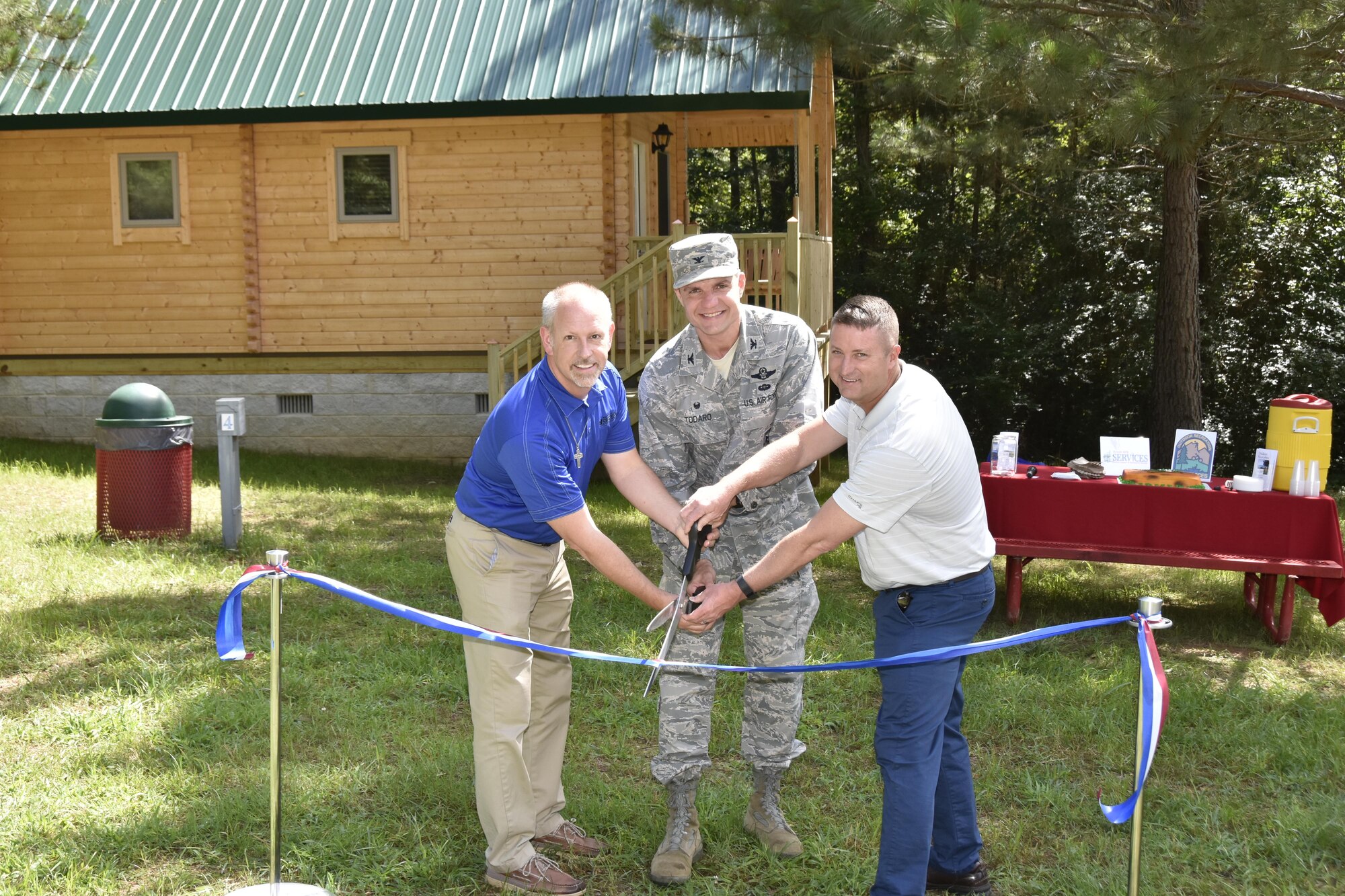 John McKelvey, Arnold Air Force Base Services Branch, AEDC Commander Col. Rodney Todaro and David Wilhite, Arnold AFB Civil Engineering Branch, cut the ribbon at the grand opening and ceremony June 20, 2017 for the Dogwood Ridge recreation area at Arnold Air Force Base. Dogwood Ridge has four fully equipped cabins with access to Woods Reservoir shore and beach area. Each cabin has heat and air, a kitchenette, bathroom, downstairs and loft bedroom, living room, and dining area. All cabins have a double bed, two twin beds and a futon which folds out to a double bed. (U.S. Air Force photo/Rick Goodfriend)