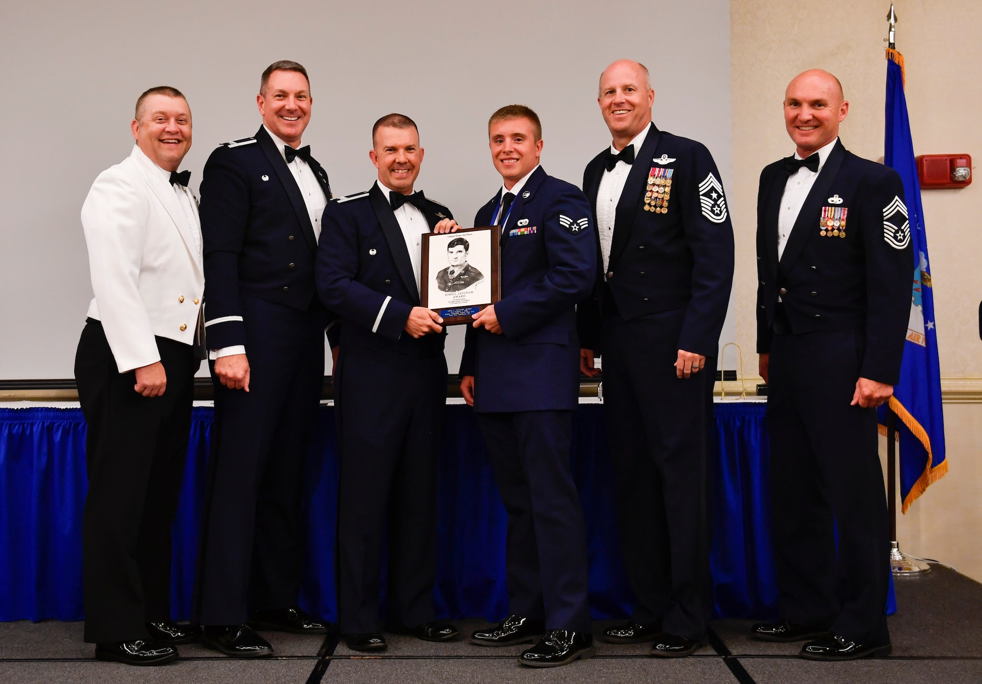 Master Chief Petty Officer Asa Worcester, left, Joint Base Charleston command master chief, Col. Robert Lyman, second from left, Joint Base Charleston wing commander, Col. Patrick Winstead, third from left, 437th Airlift Wing vice commander, Chief Master Sgt. Todd Cole, second from right, Joint Base Charleston command chief,  and Chief Master Sgt. Darrell Amoruso, right, 437th Airlift Wing acting command chief, congratulate Senior Airman Zachary Pforr, middle, 628th Logistics Readiness Squadron member, for earning the John L. Levitow Award during the class 17-E Airman Leadership School Graduation at the Charleston Club here June 29, 2017. The John L. Levitow Award is awarded to a single graduate for every Enlisted Professional Military Education course for demonstrating excellence both as a leader and scholar. 