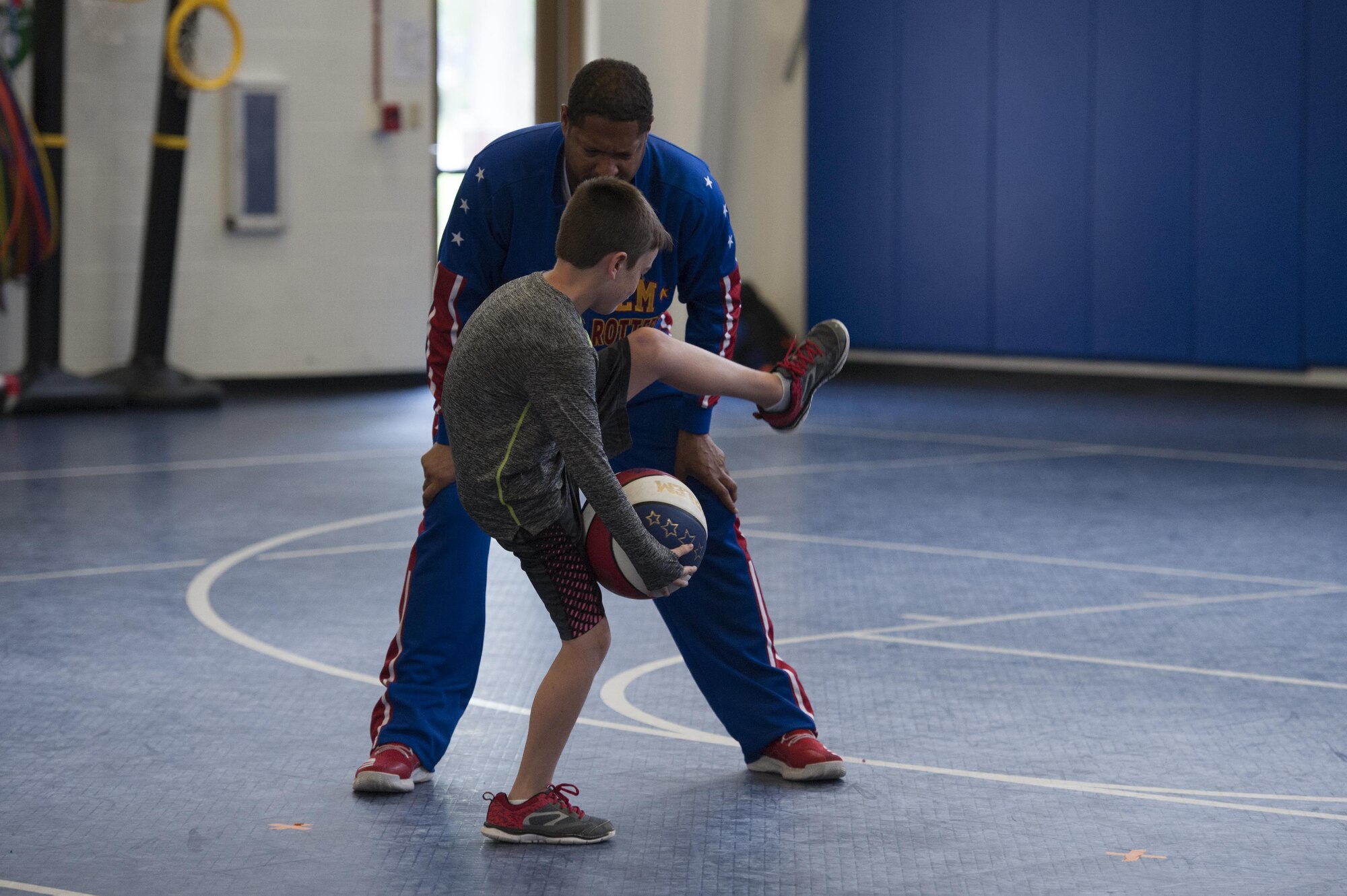 A youth center child performs a trick with Harlem Globetrotter “Handles” during a show, June 30, 2017, at Moody Air Force Base, Ga. During their visit, the globetrotters performed tricks, interacted with children, and instilled life lessons such as anti-bullying and the importance of school. (U.S. Air Force photo by Airman 1st Class Lauren M. Sprunk)