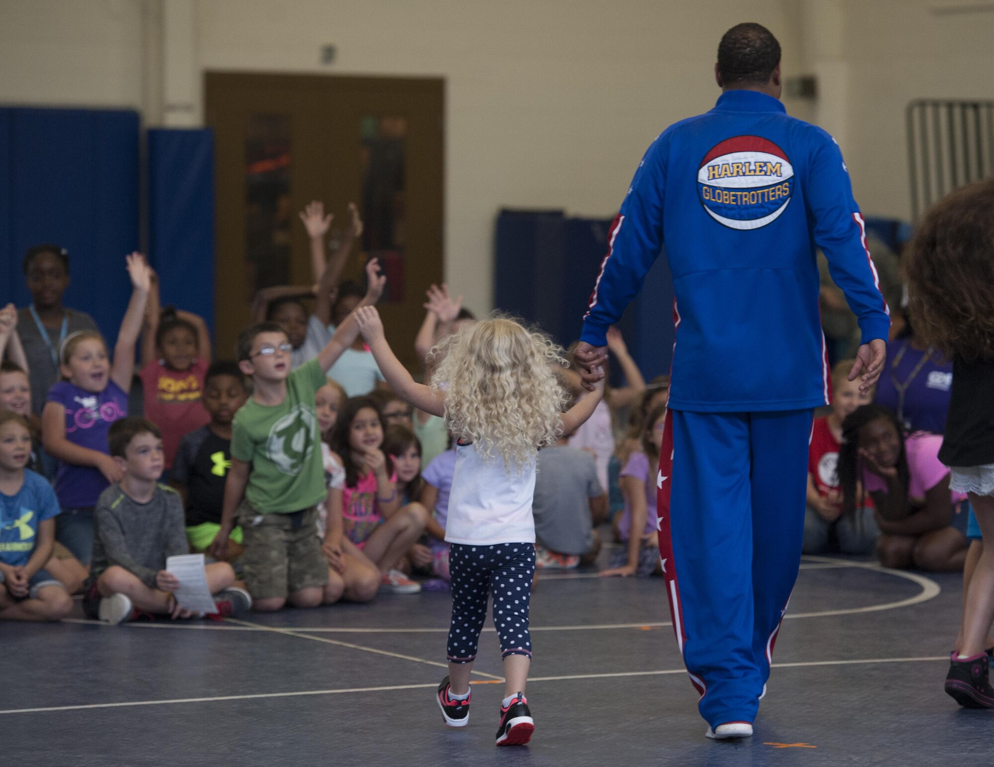 Harlem Globetrotter “Handles” walks with a youth center child during a show, June 30, 2017, at Moody Air Force Base, Ga. During their visit, the globetrotters performed tricks, interacted with children, and instilled life lessons such as anti-bullying and the importance of school. (U.S. Air Force photo by Airman 1st Class Lauren M. Sprunk)
