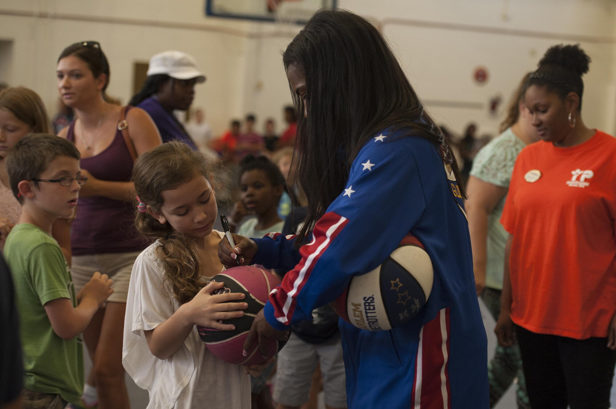 Harlem Globetrotter “TNT” signs an autograph for a youth center child after a show, June 30, 2017, at Moody Air Force Base, Ga. During their visit, the globetrotters performed tricks, interacted with children, and instilled life lessons such as anti-bullying and the importance of school. (U.S. Air Force photo by Airman 1st Class Lauren M. Sprunk)