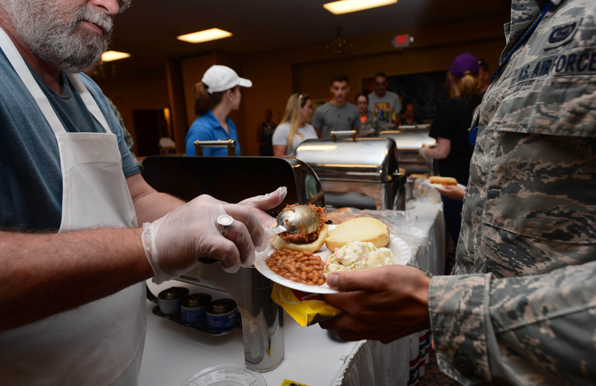 An Airman serves food in the Dakota’s Club during the annual base picnic at Ellsworth Air Force Base, S.D., June 30, 2017. During the picnic, families were served hotdogs, pulled pork sandwiches, coleslaw, beans and chips as well as a variety of drinks. (U.S. Air Force photo by Airman 1st Class Donald C. Knechtel)