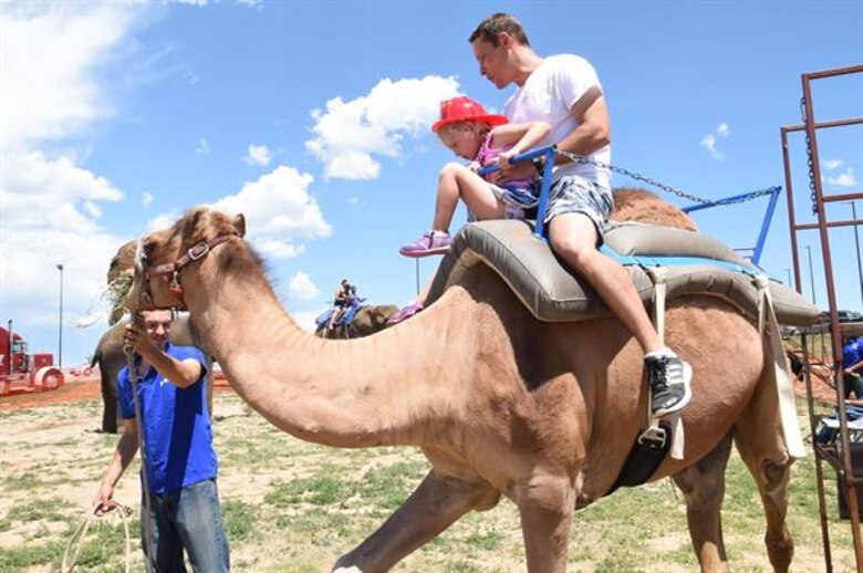 Master Sgt. Phillip Merritt, 17th Test Squadron, and his daughter, Rylee, ride a camel during the Summer Slam Base Picnic at Schriever Air Force Base, Colorado, July 15, 2016. Pony rides will be a new addition to the camel and elephant rides for this year’s picnic (U.S. Air Force photo/2nd Lt. Darren Domingo)