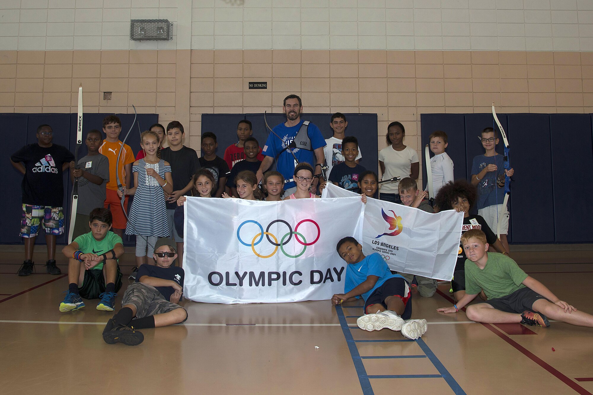 Vic Wunderle, an Olympic archer, pauses for a photo with archery camp students at the Youth Center on MacDill Air Force Base, Fla., June 23, 2017. The camp culminated with a shooting tournament to celebrate Olympic Day. (U.S. photo by Airman 1st Class Caleb Nunez)