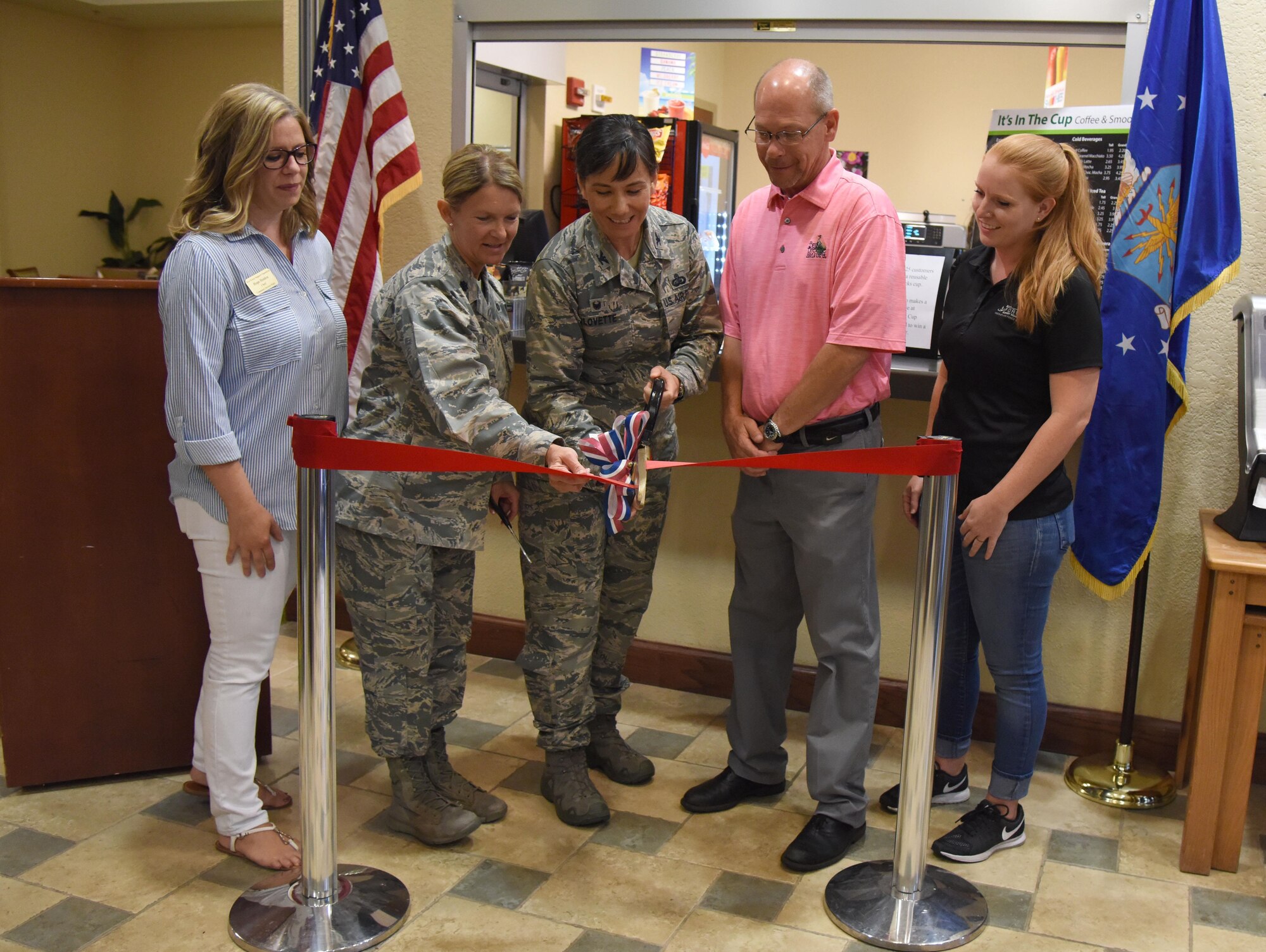 Lt. Col. Teresa King, 81st Force Support Squadron commander, and Col. Debra Lovette, 81st Training Wing commander, are joined by the 81st FSS community services flight and Bay Breeze golf course members during the “It Is In The Cup” ribbon cutting ceremony in the Bay Breeze Event Center June 29, 2017, on Keesler Air Force Base, Miss. Keesler's new coffee & smoothie bar serves Starbucks coffee, Frappuccino’s, iced beverages and espresso as well as Island Oasis smoothies in a variety of flavors. A full menu of items can be found at www.keesler81fss.us. (U.S. Air Force photo by Kemberly Groue)