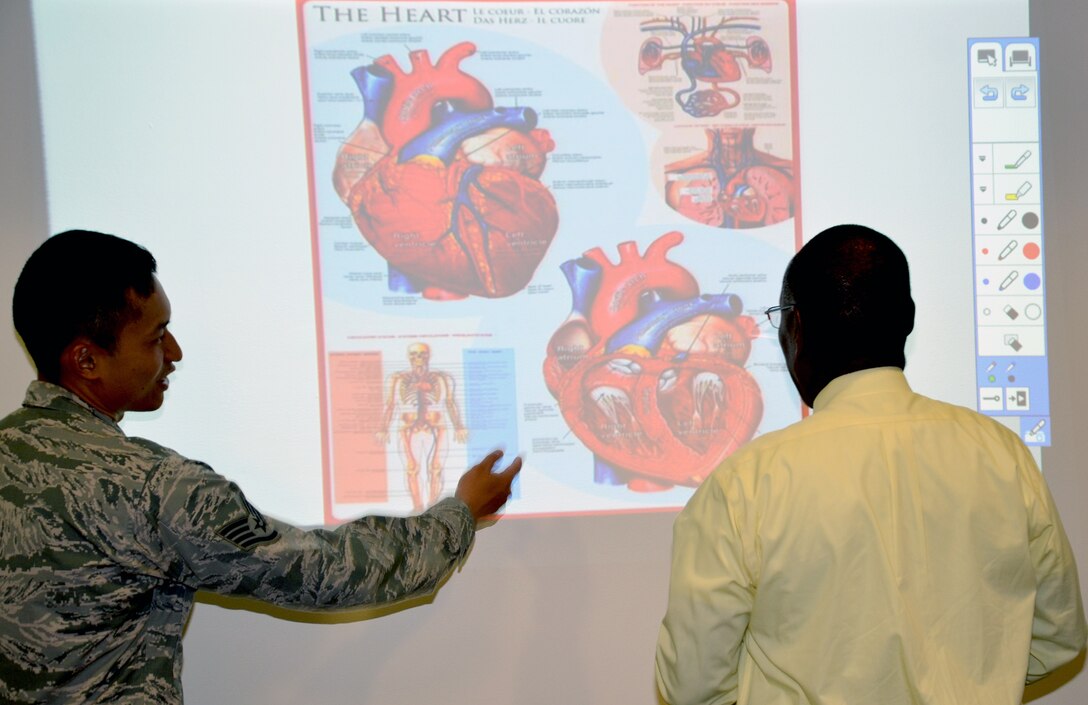 Senior Airman Travis Napaepae (left), Medical Education and Training Campus Information Management Division call center manager, and Eustace Lewis, METC  instructional system specialist, talk about the interactive SMART screen display of a heart.  