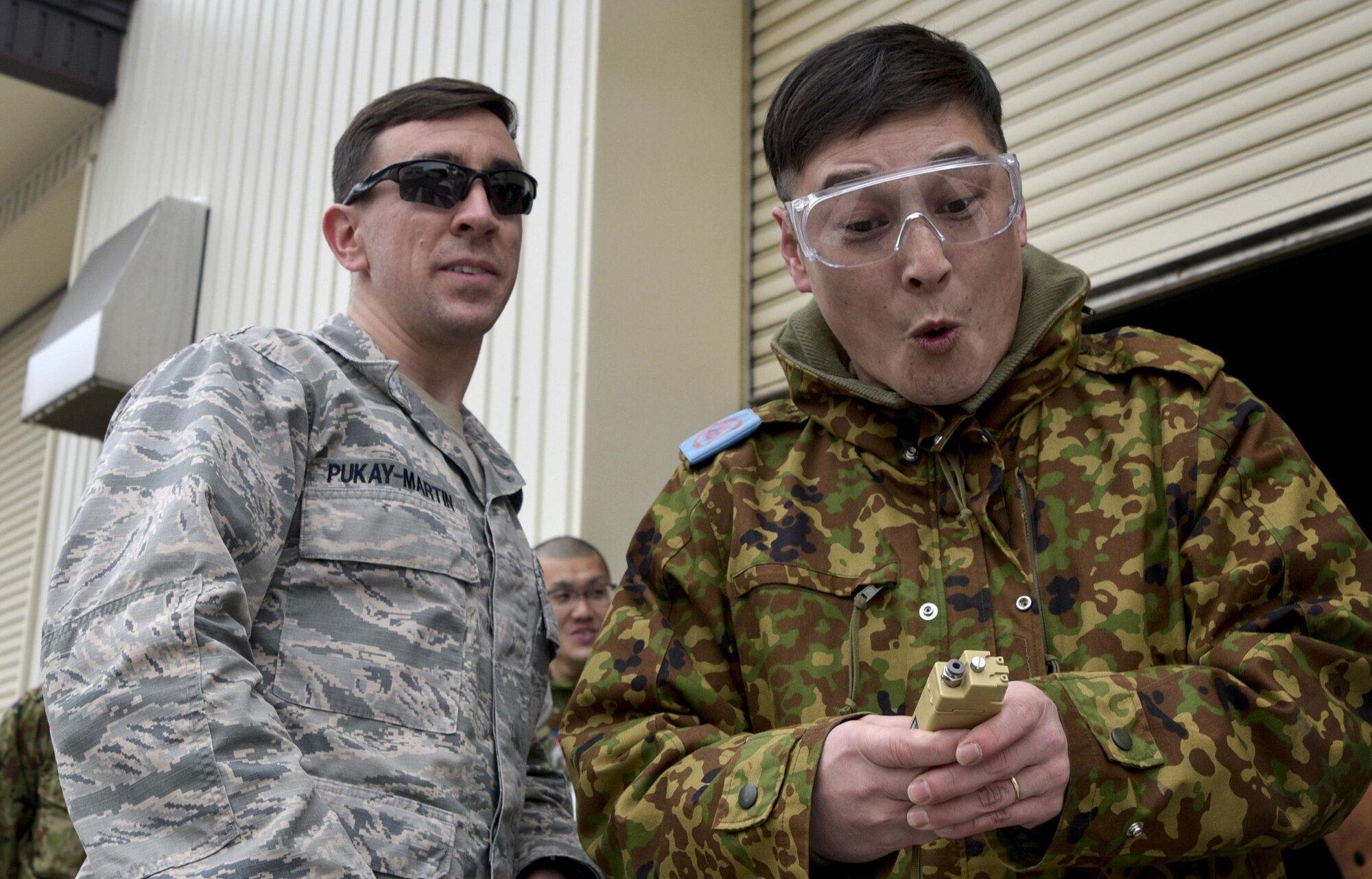 Sgt. 1st Class Kimihrio Shibazaki, an infantryman with the Japan Ground Self-Defense Force, right, initiates the percussion actuated neutralizer as Capt. Robert Pukay-Martin, 35 Civil Engineer Squadron explosive ordinance disposal flight commander, left, shares how he uses the device during contingency operations during a three-day English comprehensive tour at Misawa Air Base, Japan, Feb. 22, 2017. A PAN is a tool that explosive ordinance disposal technicians use to disarm improvised explosive devices. (U.S. Air Force photo by Staff Sgt. Melanie A. Hutto)