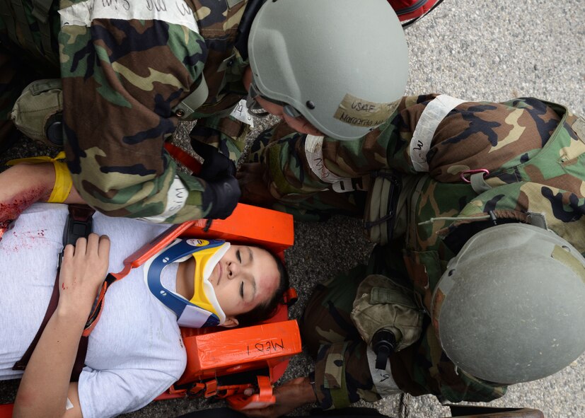 U.S. Air Force Airman 1st Class Quinton Sanders, right, 51st Civil Engineer Squadron heating, ventilation, and air conditioning specialist, assists while Tech. Sgt. Margarita Mailander, 51st Medical Group independent duty medical technician, straps down Airman 1st Class Thalia Haslow, 51st Logistics Readiness Squadron outbound cargo specialist, to a stretcher during Exercise Beverly Herd 17-1 at Osan Air Base, Republic of Korea, March 1, 2017. Civil Engineer, Medical and Logistics Readiness personnel worked cohesively to assess the capabilities of first-responders in a simulated environment. (U.S. Air Force photo by Tech. Sgt. Ashley Tyler)