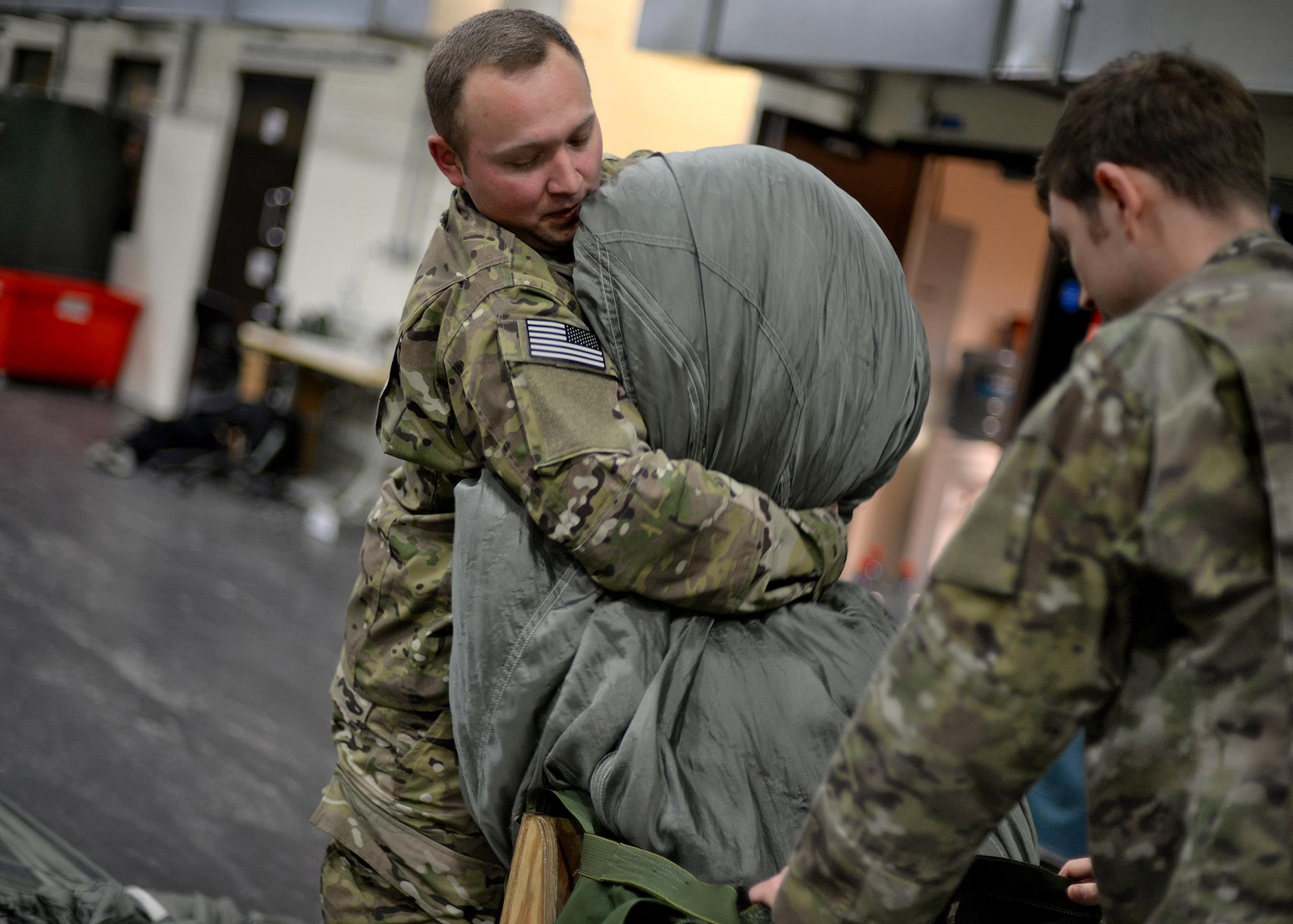 U.S. Air Force Staff Sgt. Brian Demik, left, and U.S. Air Force Staff Sgt. Nicholas Brunjes, both 352d Special Operations Support Squadron aerial delivery riggers, pack a parachute Feb. 15, 2017, on RAF Mildenhall, England. Rigger pack a variety of parachutes, including 28-feet, 26-feet and 15-feet chutes, 68-inch pilot parachutes, (small, auxiliary parachute used to deploy the main or reserve), and G-12 Army parachutes, along with drogues and sandbags. (U.S. Air Force photo by Senior Airman Christine Halan)