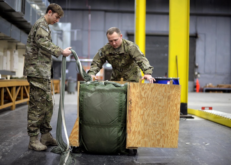 U.S. Air Force Staff Sgt. Nicholas Brunjes, left, and U.S. Air Force Staff Sgt. Brian Demik, both 352d Special Operations Support Squadron Aerial Delivery riggers, complete the process of packing a parachute Feb. 15, 2017, on RAF Mildenhall, England. Rigger pack a variety of parachutes, including 28-feet, 26-feet and 15-feet chutes, 68-inch pilot parachutes, (small, auxiliary parachute used to deploy the main or reserve), and G-12 Army parachutes, along with drogues and sandbags. (U.S. Air Force photo by Senior Airman Christine Halan)