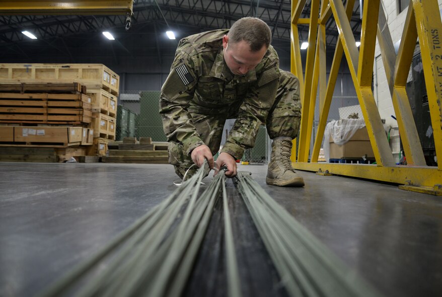 U.S. Air Force Staff Sgt. Brian Demik, 352d Special Operations Support Squadron aerial delivery rigger, untangles parachute cords Feb. 15, 2017, on RAF Mildenhall, England. The aerial delivery flight have the capability of sewing the parachutes for on the spot repairs, anytime there is a hole, tear or friction burn. (U.S. Air Force photo by Senior Airman Christine Halan) 