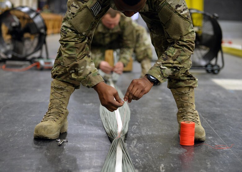 U.S. Air Force Staff Sgt. Jarryd Dooley, 352d Special Operations Support Squadron Aerial Delivery rigger, and U.S. Air Force Staff Sgt. Brian Demik, 352d SOSS Aerial Delivery rigger, secure a parachute Feb. 15, 2017, on RAF Mildenhall, England. They also have their own wood shop to build up platform on which the cargo is strapped, and it takes approximately 13.5 man hours to create a platform from start to finish.(U.S. Air Force photo by Senior Airman Christine Halan) 