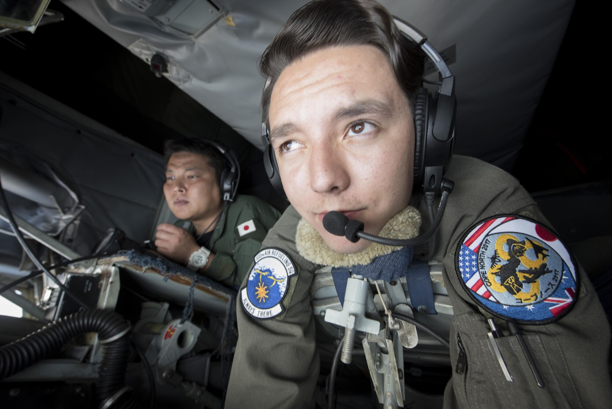 U.S. Air Force Airman 1st Class Luke Story, 909th Air Refueling Squadron boom operator, prepares to conduct aerial refueling while being observed by Japan Air Self-Defense Force 1st Lt. Yoshifumu Takase March 1, 2017, off the coast of Guam. The refueling was conducted for exercise Cope North, an annual gathering of Japanese, U.S. and Australian service members who train to increase combat readiness and interoperability. (U.S. Air Force photo by Senior Airman John Linzmeier)