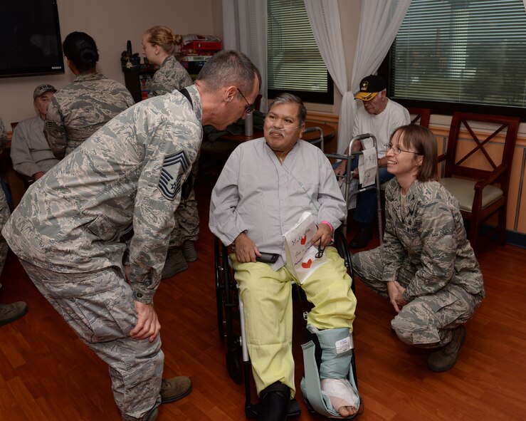 Chief Master Sgt. Michael Marshall (left), 88th Air Base Wing band manager, and Col. Elena Oberg, 88th Air Base Wing vice commander, chat with Juan Veloz, Marine Corps veteran and patient at Dayton Veteran Affairs Medical Center, Feb. 14. All VA medical facilities, VA outpatient clinics, and state veterans homes observe annually the National Salute to Veterans the week of Valentine’s Day, a day of expressing appreciation to veterans. (U.S. Air Force photo/Michelle Gigante)