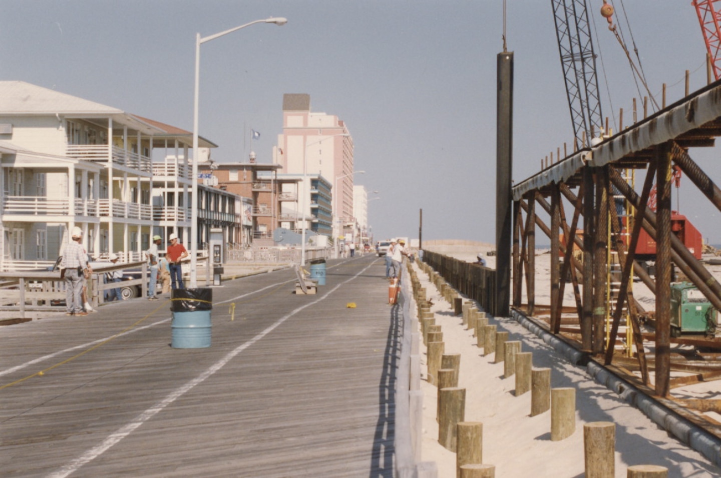 Crews work to construct the steel sheet piling bulkhead with a concrete cap that rises 14.5 feet above National Geodetic Vertical Datum along the oceanward edge of the boardwalk in 1991. These boardwalk improvements, working in concert with the wide, elevated beach berm between the boardwalk and the ocean, provide coastal storm risk management to Ocean City during storm events.