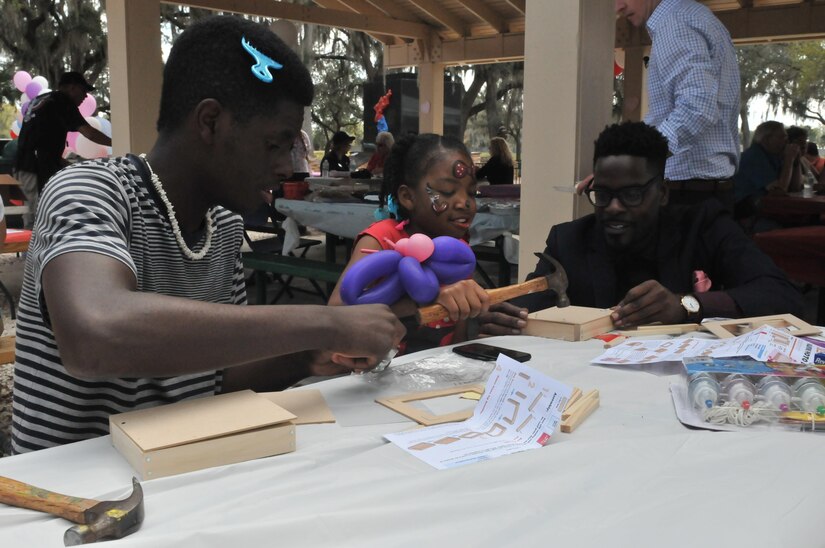 Jerimiah Robinson (left) and cousin, Denareya Owens (middle), create memory boxes with the help of Marc Aghedo (right), 335th Signal Command’s Director of Army Reserve Child, Youth and School Services. The boxes are created and dedicated to fallen service members, and Robinson is dedicating his box for his uncle who died in Vietnam, and Owens for her grandfather who died in World War II.  This activity is part of Operation Love Letters, which  is an annual patriotic celebration to honor fallen service members through fellowship with family and friends gathered together writing love letters, scripting poetry, sharing loveable memories of their service member, and enjoying the offerings of some very special guests. This year, the event was held at Veterans Memorial Park in Tampa on Feb. 19, 2017.