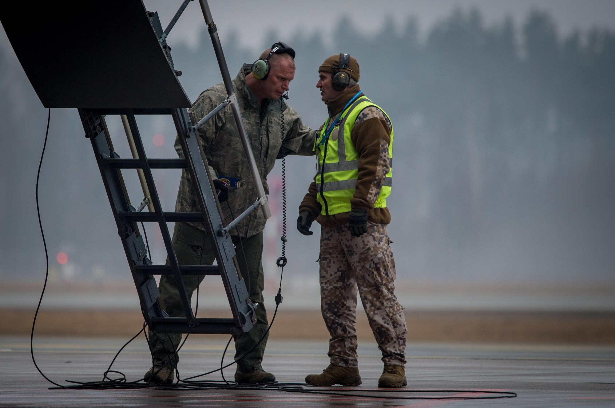 A U.S. Air Force crew chief and a Latvian soldier coordinate unloading a C-5M Super Galaxy at Riga International Airport, Latvia, Mar. 1, 2017, where it delivered UH-60 Black Hawk helicopters for the U.S. Army in support of Operation Atlantic Resolve. Five Black Hawk helicopters will be deployed to Latvia as part of a larger contingent of helicopters and personnel deployed to support Operation Atlantic Resolve, a U.S. commitment to maintaining peace and stability in the European region. (U.S. Air Force photo/Tech. Sgt. Ryan Crane)