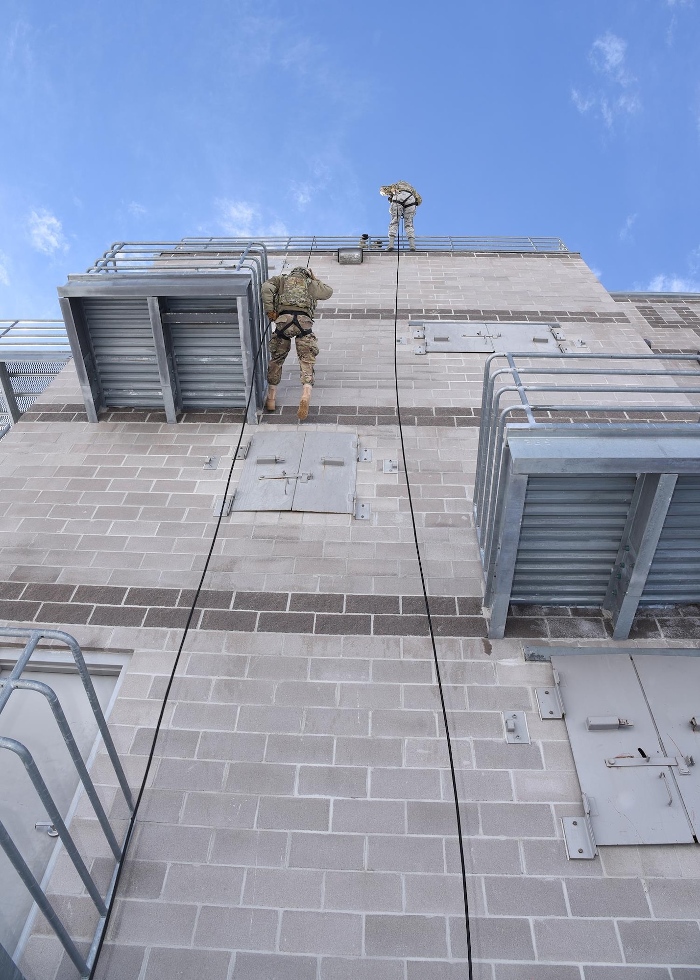 Airman 1st Class Justin Heard begins the first steps of his 70 foot decline down the rappelling rope during rappelling exercises Feb. 25 at the Cheyenne Fire Department training facility. The belaying position is a safety position to ensure the Airman rappelling has someone supporting a controlled decline. The rappelling course is designed to train future Tactical Response Force members how to properly rappel to descend quickly into a launch facility in case of emergency. (U.S. Air Force Photo by Glenn S. Robertson)