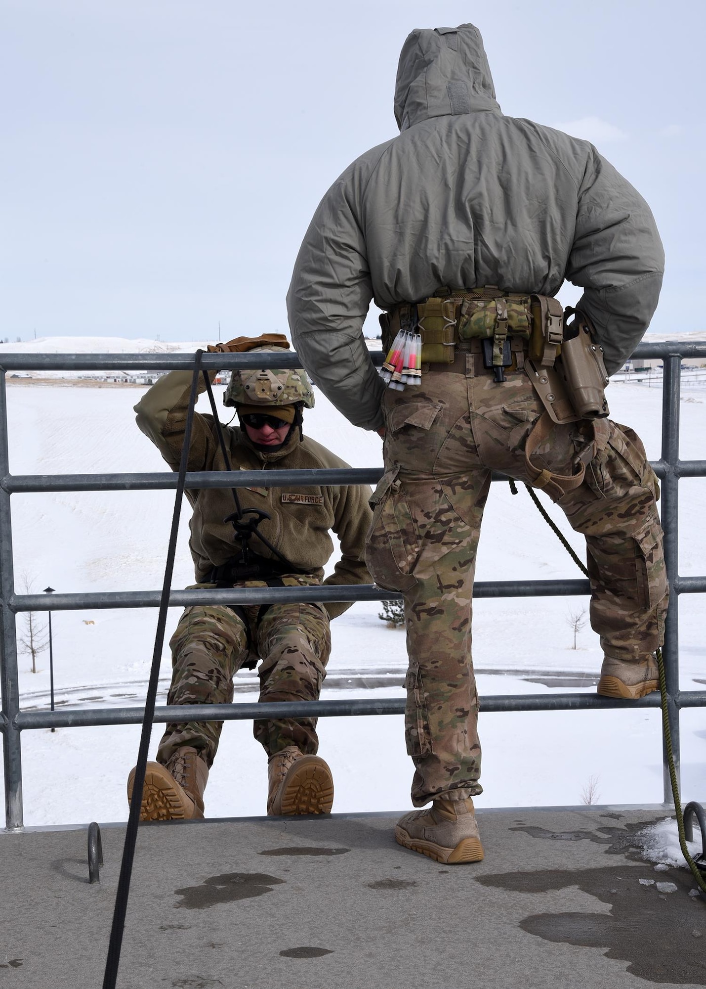 Airman 1st Class Steven Berard belays for another classmate descending the 70 foot wall during rappelling exercises Feb. 25 at the Cheyenne Fire Department training facility. The belaying position is a safety position to ensure the Airman who is rappelling has someone supporting a controlled decline. The rappelling course is designed to train future Tactical Response Force members how to properly rappel to descend quickly into a launch facility in case of emergency. (U.S. Air Force Photo by Glenn S. Robertson)