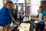 DSCC Chief of Morale, Welfare and Recreation Brandon Doherty slices cake at the Feb. 27 re-opening ceremony for the Defense Supply Center Columbus Child Development Center. The event recognized the CDC's first day operating as an in-sourced, installation managed facility. Also pictured are DSCC Site Director Dan Bell (center left), Defense Logistics Agency Installation Director Denise Miller (center right) and MWR Marketing Manager Jennifer Russell.