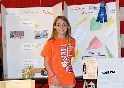Savannah Altine, 11, a fourth-grade student at Marrington Elementary (MNE) School, located at Joint Base Charleston – Weapons Station, poses in front of her science fair project following the MNE Science Fair Feb. 21. Altine earned "First Prize" for her project, "Can the Design of a Paper Airplane Make it Go Farther?"