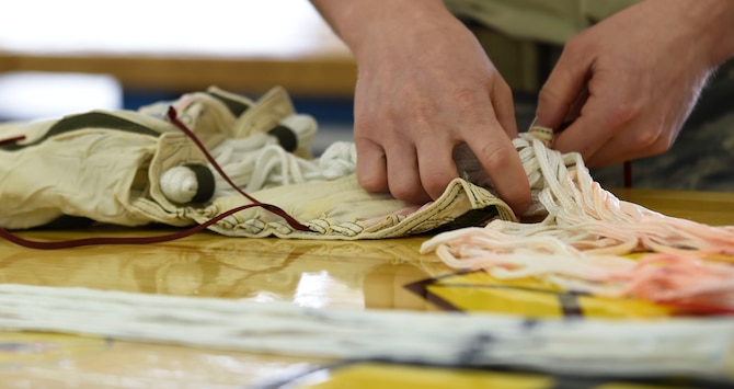 U.S. Air Force Senior Airman Tyler Wineman, 1st Operation Support Squadron aircrew flight equipment technician, stows parachute lines on a T-38 Talon drogue parachute at Joint Base Langley-Eustis, Va., Feb. 27, 2017. The AFE parachute shop inspects parachutes regularly to ensure its proper deployment in case of an emergency. (U.S. Air Force photo by Staff Sgt. Natasha Stannard)