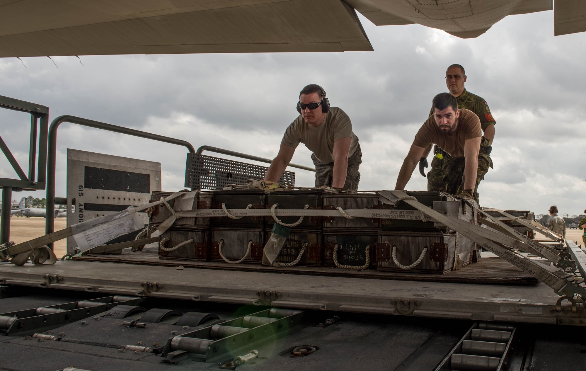 A U.S. Airman left, and a Royal Canadian Air Force member, push a pallet onto a C-130J Super Hercules aircraft during a Joint Readiness Training exercise, Feb. 11, 2016, at Alexandria International Airport, LA. During the exercise, the two countries integrated their aerial port operations to get a better understanding on how each country operate while loading aircraft. (U.S. Air Force photo by Staff Sgt. Robert Hicks) 