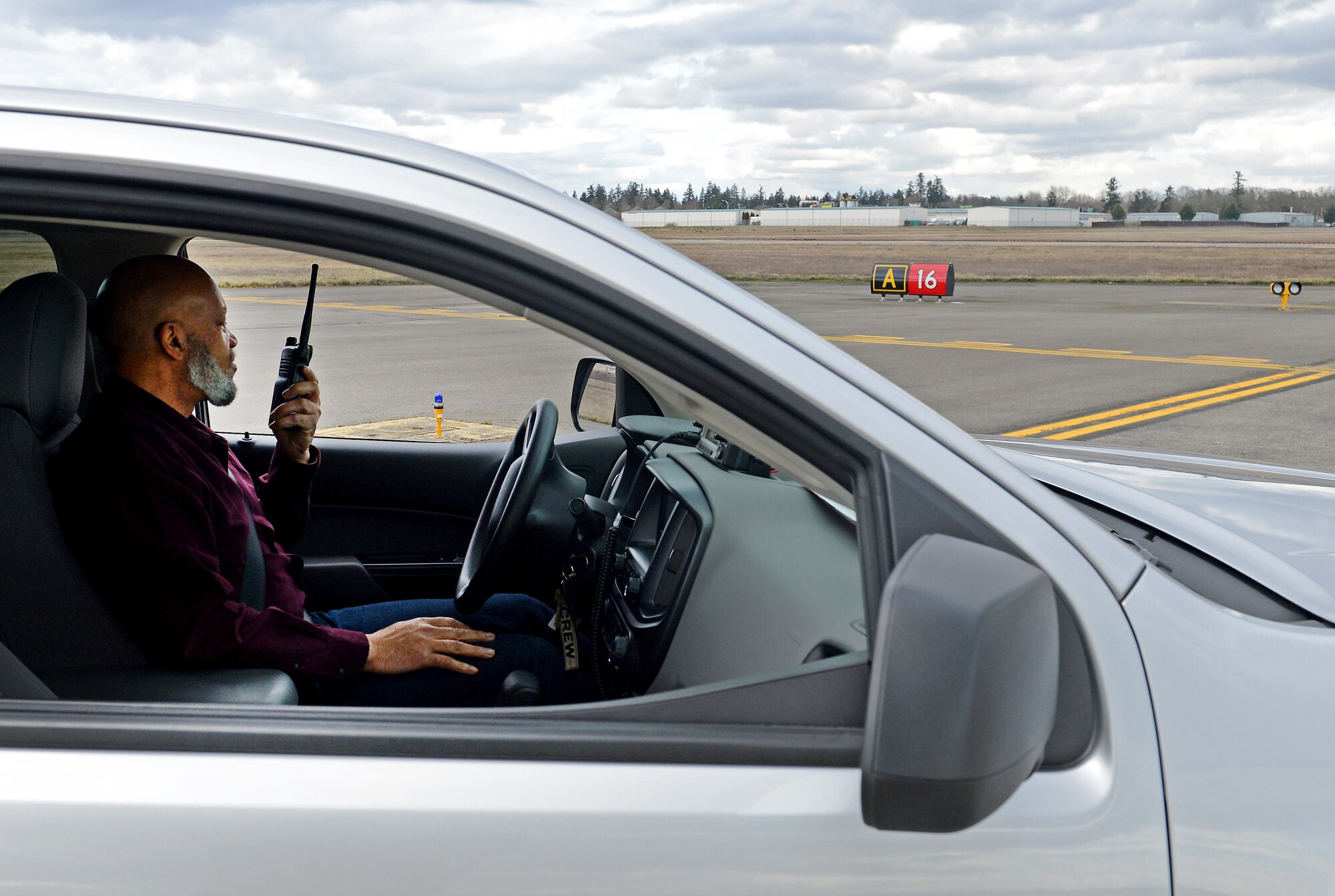 To avoid a runway incursion, Mr. Urouse Williams, 62nd Airlift Wing airfield driving program manager, demonstrates the proper way of contacting the air traffic control tower for clearance to drive on the McChord airfield Feb. 28, 2017 at Joint Base Lewis-McChord, Wash. A runway incursion is any unauthorized presence of an aircraft, vehicle or person on the safety protected area of a surface designated for the landing and take-off of aircraft. (U.S. Air Force photo/Senior Airman Divine Cox)