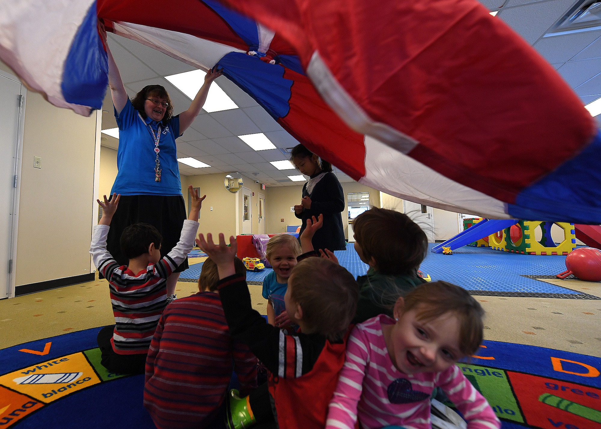 Michele Southall, Grand Forks Air Force Base Child Development Center lead program technician, lifts a parachute over her students Feb. 28, 2017, on Grand Forks AFB, N.D. Southall recently received the Terri Lynne Lokoff/Children’s TYLENOL® National Child Care Teacher Award thanks to her daily work and dedication to her students. (U.S. Air Force photo by Senior Airman Ryan Sparks)