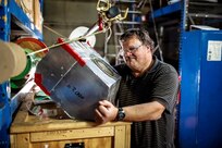 Norfolk Naval Shipyard employee Paul Foster works on a noise attenuator he designed for drying towers used to create freeze seals. The attenuator has reduced noise levels in the work area from 108 decibels to 84 decibels, reducing the risk of hearing loss by workers and eliminating the need for double hearing protection.