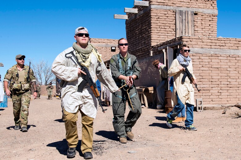 Mock friendly locals from a Southwest Asian bazaar escort a U.S. Marine aircrew member during a simulated Tactical Recovery of Aircraft and Personnel scenario, Feb 22, 2017, at the Playas Training and Research Center, N.M. During the scenario, Marines from I Marine Expeditionary Force from Marine Corps Base Camp Pendleton, Calif., rescued isolated personnel from a downed aircraft while fending off mock opposition forces from Davis-Monthan Air Force Base, Ariz.’s 563d Operations Support Squadron. This joint effort prepared the IMEF by completing their Special Purpose Marine Air Ground Task Force certification. This is the culmination of their crisis response operations before deploying to the United States Central Command, which consists of 20 countries In Northeast Africa and Southwest Asia. (U.S. Air Force photo by Airman 1st Class Greg Nash)   