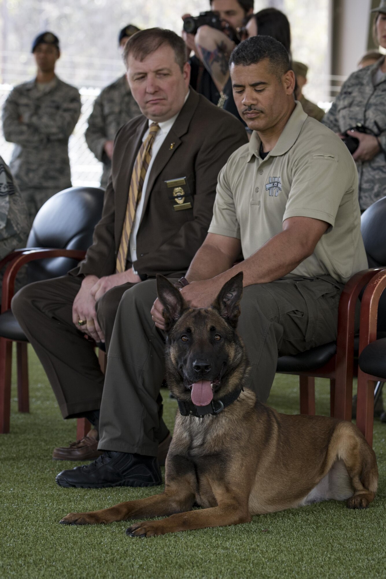 Military working dog SSmokey sits beside his new handler, Officer Jose Cruz, Valdosta Police Department K-9 handler, during a MWD leash transfer ceremony, Feb. 28, 2017, at Moody Air Force Base, Ga. Ssmokey was transferred from the care of Staff Sgt. Jason Ashmore, 23d SFS MWD trainer, to Cruz, where he will continue his work as an explosive detective dog in the local community. (U.S. Air Force photo by Airman 1st Class Lauren M. Sprunk)