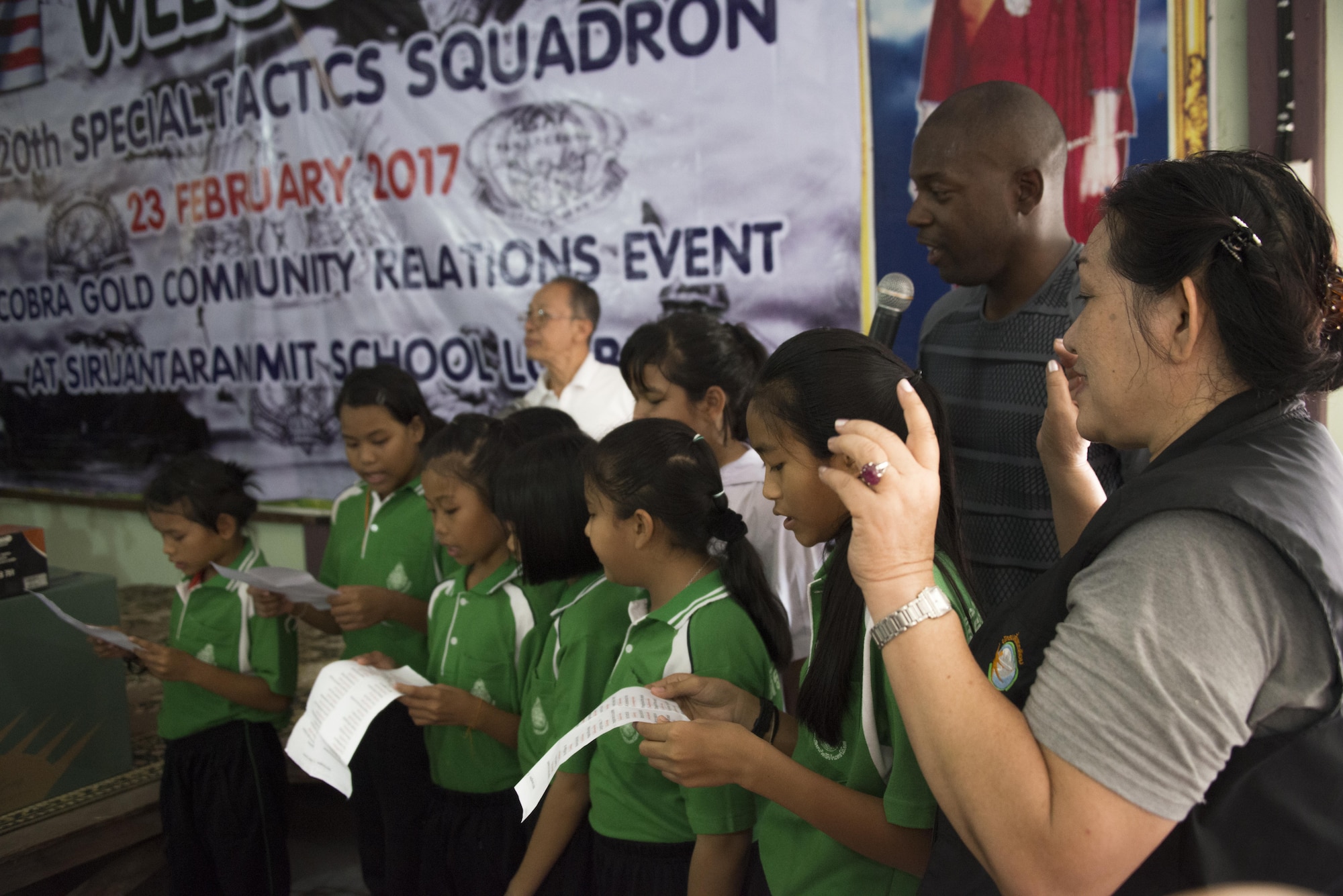 U.S. Air Force Tech Sgt. Venie Joshua, 353rd Special Operations Support Squadron aircrew flight equipment technician, sings with Thai students from Sirijantaranmit School Lopburi during a community relations event in Lopburi, Thailand, Feb. 23, 2017. The military members demonstrated appreciation to the local community following Cobra Gold 2017 with a day of activities, which included a soccer game, luncheon, bilateral jump demonstration and flyover. (U.S. Air Force photo by Capt. Jessica Tait)