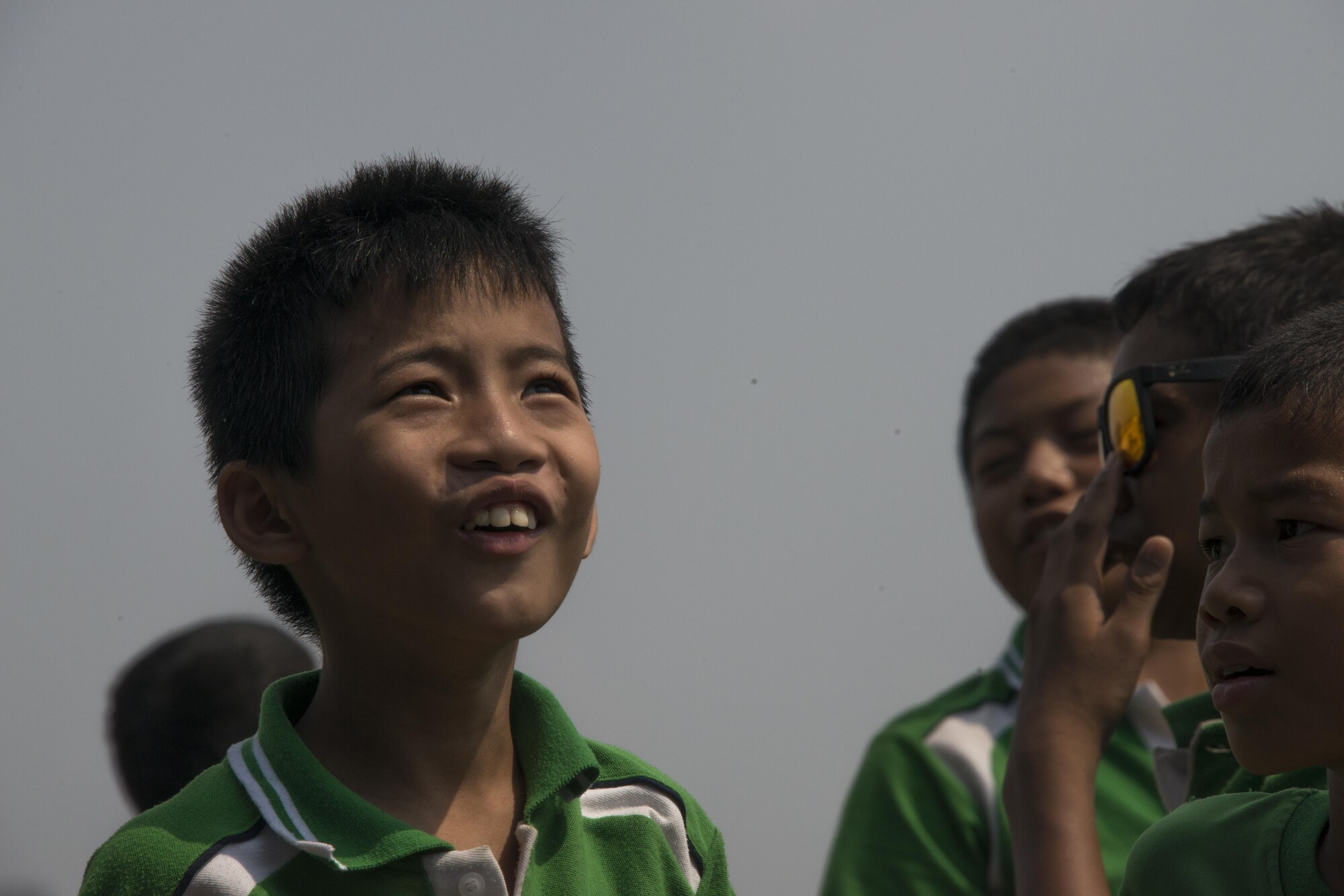 Thai students from Sirijantaranmit School Lopburi watch the drop zone as combat controllers and pararesucement from the Royal Thai Air Force Special Operations Regiment and 320th Special Tactics Squadron jump from a U.S. Air Force MC-130J Commando II assigned to the 17th Special Operations Squadron, Feb. 23, 2017 at Thai Air Force Base Wing 2 in Lopburi, Thailand. The military members demonstrated appreciation to the local community following Cobra Gold 2017 with a day of activities, which included a soccer game, luncheon, bilateral jump demonstration and flyover. (U.S. Air Force photo by Capt. Jessica Tait)
