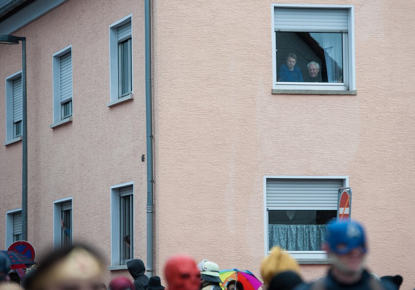 An elderly couple stare out their window to view the parade below them during fasching, a festival held across Europe, in the city of Ramstein, Germany, Feb. 28, 2017. Fasching is a time of festivity and merry making—a time where common place people take a chance to free themselves for personal expression and celebration. (U.S. Air Force photo by Senior Airman Lane T. Plummer)