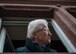 An elderly woman leans out her window to observe the festivities below her apartment during fasching, a festival held across Europe, in the city of Ramstein, Germany, Feb. 28, 2017. While people are encouraged to come down to the streets to celebrate with the parade crowds, older citizens tend to watch from within their homes. (U.S. Air Force photo by Senior Airman Lane T. Plummer)