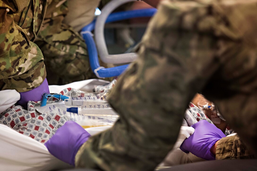 Airmen place a patient onto a litter at the Kandahar Regional Military Hospital, Kandahar Airfield, Afghanistan, Feb. 22, 2017. Air Force photo by Staff Sgt. Katherine Spessa