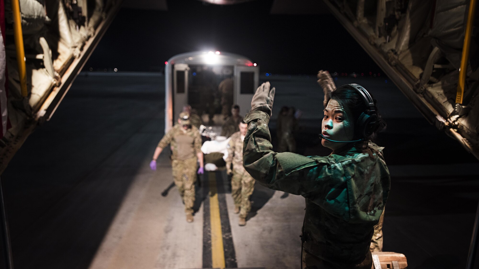 1st Lt. Sarah Jun, 455th Aeromedical Evacuation Squadron flight nurse, directs litter carriers bringing a patient onboard a C-130J Hercules to transport him from Kandahar Regional Military Hospital, Kandahar Airfield, to the Craig Joint Theater Hospital, Bragram Airfield, Afghanistan Feb. 22, 2017. The 455th EAES creates and operates a portable intensive care unit aboard aircraft that enables them to transport critically injured or ill patients to a higher level of care. (U.S. Air Force photo by Staff Sgt. Katherine Spessa)