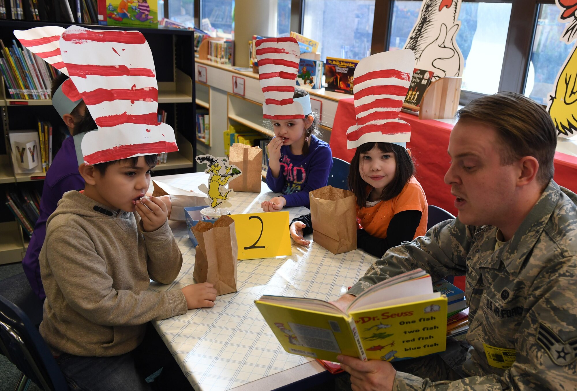 Senior Airman Tyler Allen, U.S. Air Forces Europe Warrior Prep Center systems administrator, reads to elementary school students during the Seuss Reading Café at Ramstein Air Base, Germany, March 3, 2017. More than 50 service members volunteered to read to students during the week-long event. (U.S. Air Force photo by Staff Sgt. Nesha Humes) 