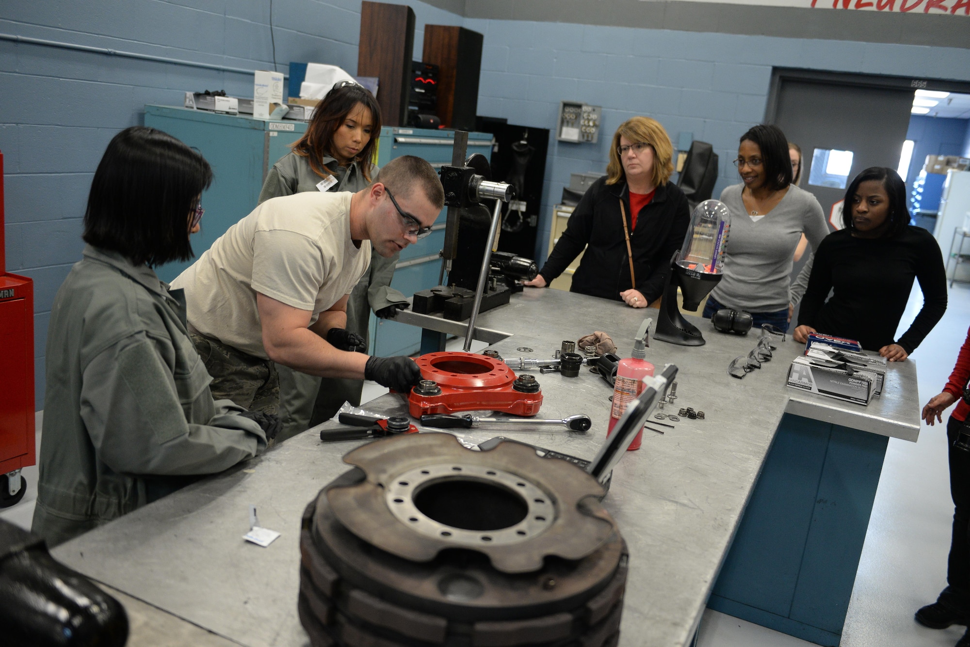 Airman 1st Class Kameron Hamilton, a 55th Maintenance Squadron hydraulics system journeyman, shows 55th MXS spouses how to work on a RC-135 break assembly part in the Bennie L. Davis Maintenance Facility at Offutt Air Force Base, Neb., Feb. 17, 2017. The tour was designed to show spouses what their significant others do to support the Air Force mission.(U.S. Air Force photo by Zachary Hada)