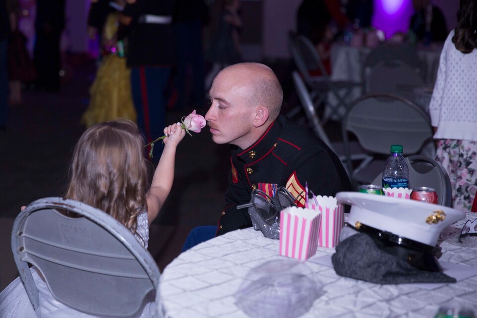 Cpl. Justin Falcon, automotive organizational mechanic, 7th Marine Regiment, smells a rose presented by his daughter, Madelyn, 4, during the annual Father Daughter Dance at building 1707 aboard Marine Corps Air Ground Combat Center, Twentynine Palms, Calif., Feb. 25, 2017. Marine Corps Community Services hosted the event to provide an opportunity for Marines and sailors to spend time with their daughters. (U.S. Marine Corps photo by Lance Cpl. Natalia Cuevas)