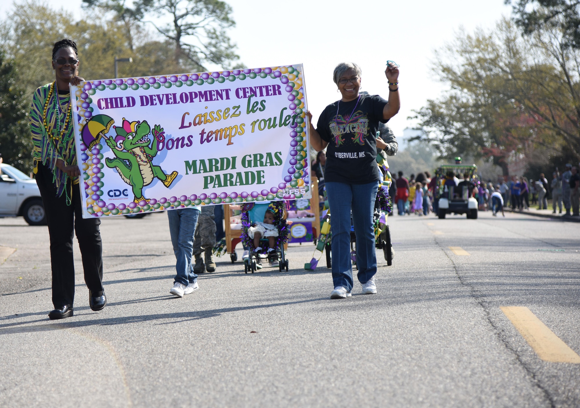 Sadaki Lewis, 81st Force Support Squadron child development center program supervisor, and Juanita Harper, CDC assistant director, hold a banner during the center’s Mardi Gras parade Feb. 28, 2017, on Keesler Air Force Base, Miss. More than 300 children participated in the event, which started in 2009. (U.S. Air Force photo by Kemberly Groue)