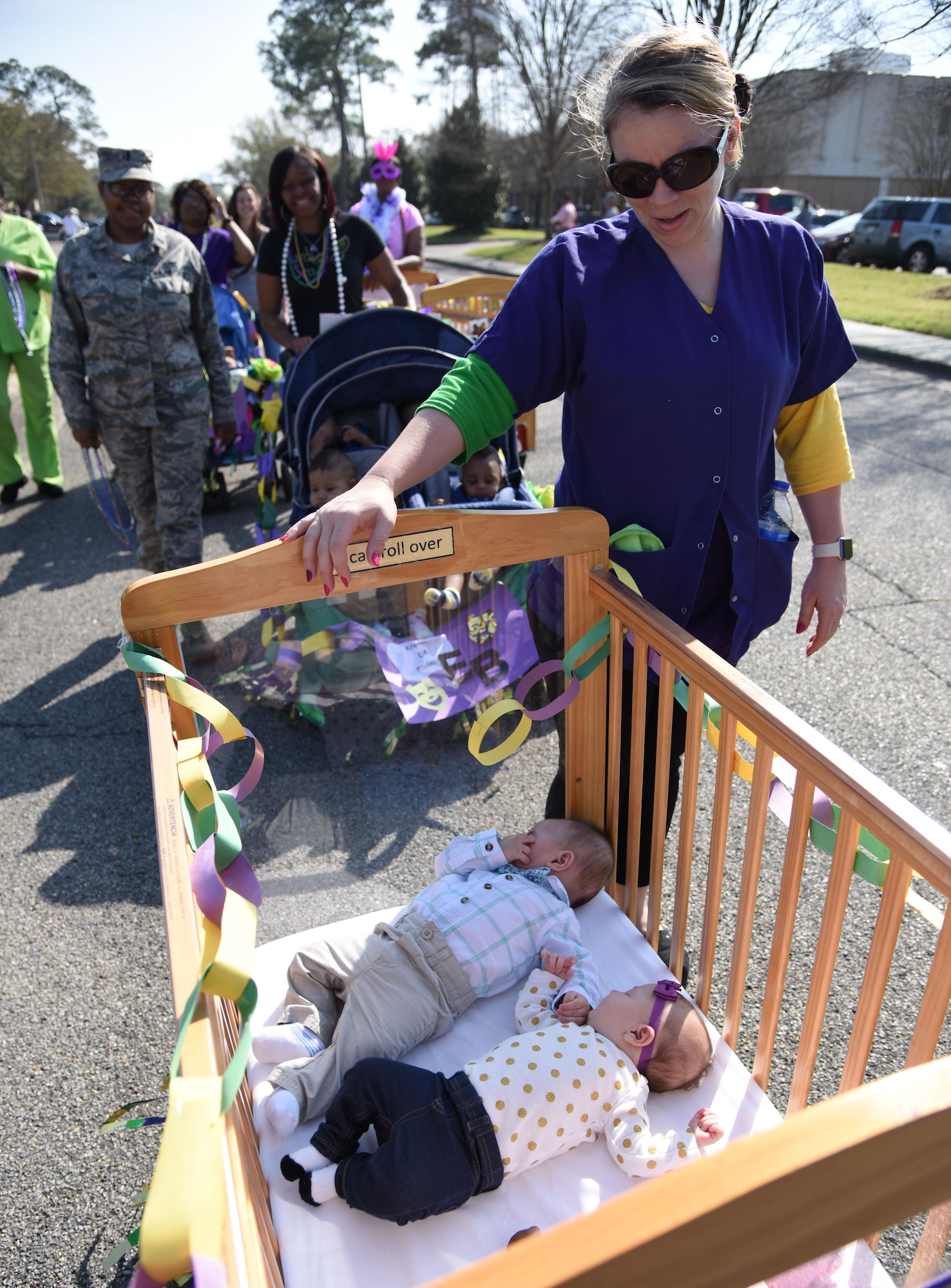 Jami Smith, Keesler Child Development Center care provider, walks alongside a crib with children during the center’s Mardi Gras parade Feb. 28, 2017, on Keesler Air Force Base, Miss. More than 300 children participated in the event, which started in 2009. (U.S. Air Force photo by Kemberly Groue)