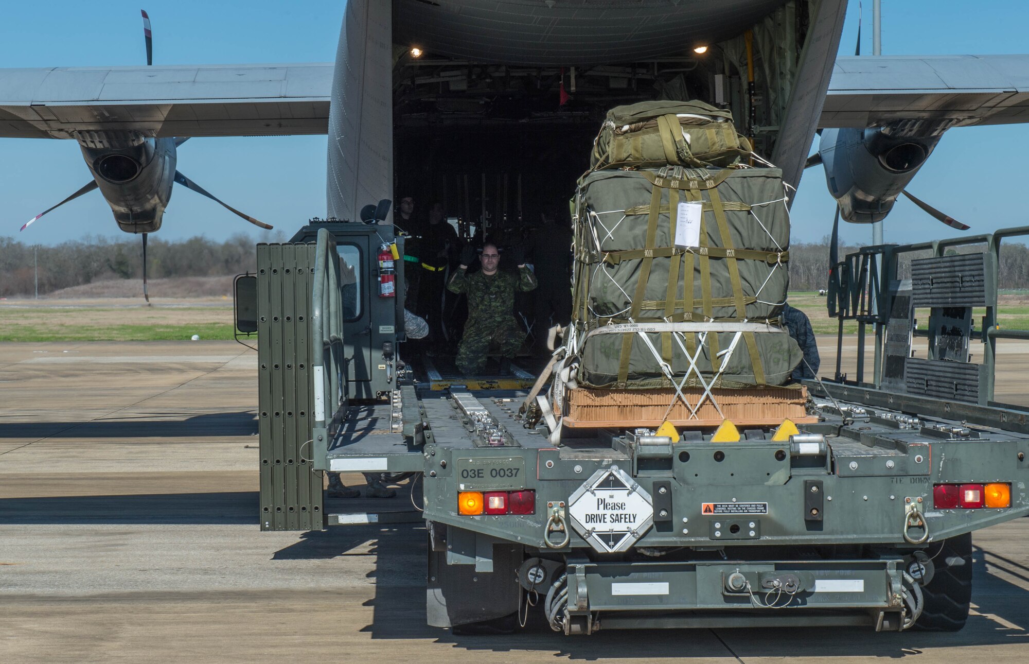 A member of the Royal Canadian Air Force, spots a K-loader during a Joint Readiness Training exercise, Feb. 10, 2016, at Alexandria International Airport, LA. During the exercise, the two countries integrated their aerial port operations to get a better understanding on how each country operate while loading aircraft. (U.S. Air Force photo by Staff Sgt. Robert Hicks)