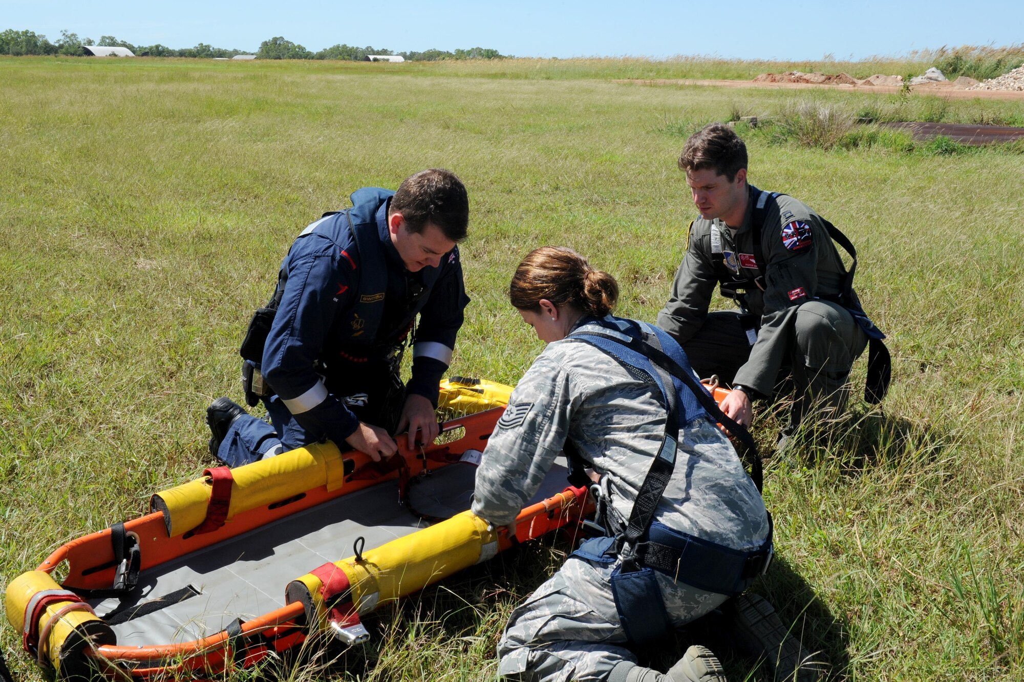 Rescue Crewman Kurt Pride, Royal Australian Air Force Base Tindal helicopter unit member, U.S. Air Force Capt. Paul Ward, 90th Fighter Squadron Flight Doctor, and Tech. Sgt. Layla Dispense, 90th FS Independent Duty Medical Technician, prepare a dummy for transport on a stretcher during helicopter rescue training at RAAF Base Tindal, Feb. 28, 2017. Ward and Dispense are deployed to Australia as part of the Enhanced Air Cooperation, a joint training and exercise initiative under the Force Posture Agreement between the U.S. and Australian governments. (U.S. Air Force photo by Staff Sgt. Alexander Martinez)