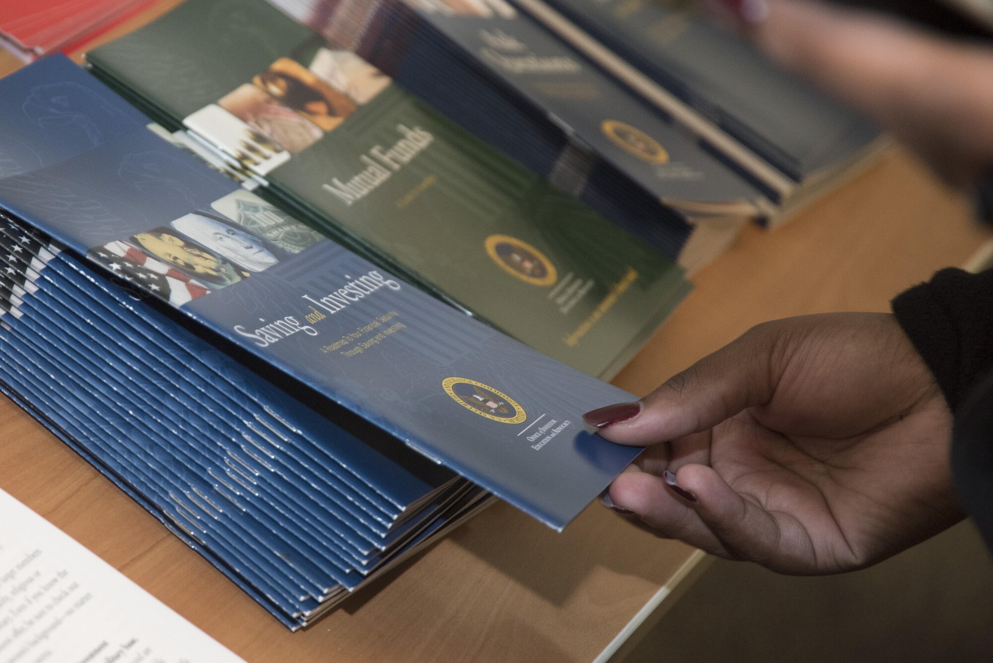 A Military Saves Week event attendee takes a Saving and Investing pamphlet at Joint Base Andrews, Md., March 3, 2017. The week was dedicated to educating Department of Defense personnel about personal financial matters ranging from debt reduction to retirement planning. (U.S. Air Force photo by Senior Airman Jordyn Fetter)