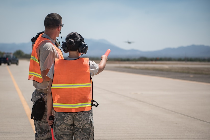 Air Force Staff Sgt. Alisha Garrette and crew chief Staff Sgt. Sean Sullivan watch a C-130 Hercules aircraft land while participating in the 612th Air Base Squadron's "Crew Chief for a Day" program at Soto Cano Air Base, March 2. The program aims to get other servicemembers from JTF-Bravo to come out to the airfield and experience a day in the life of a U.S. Air Force crew chief.